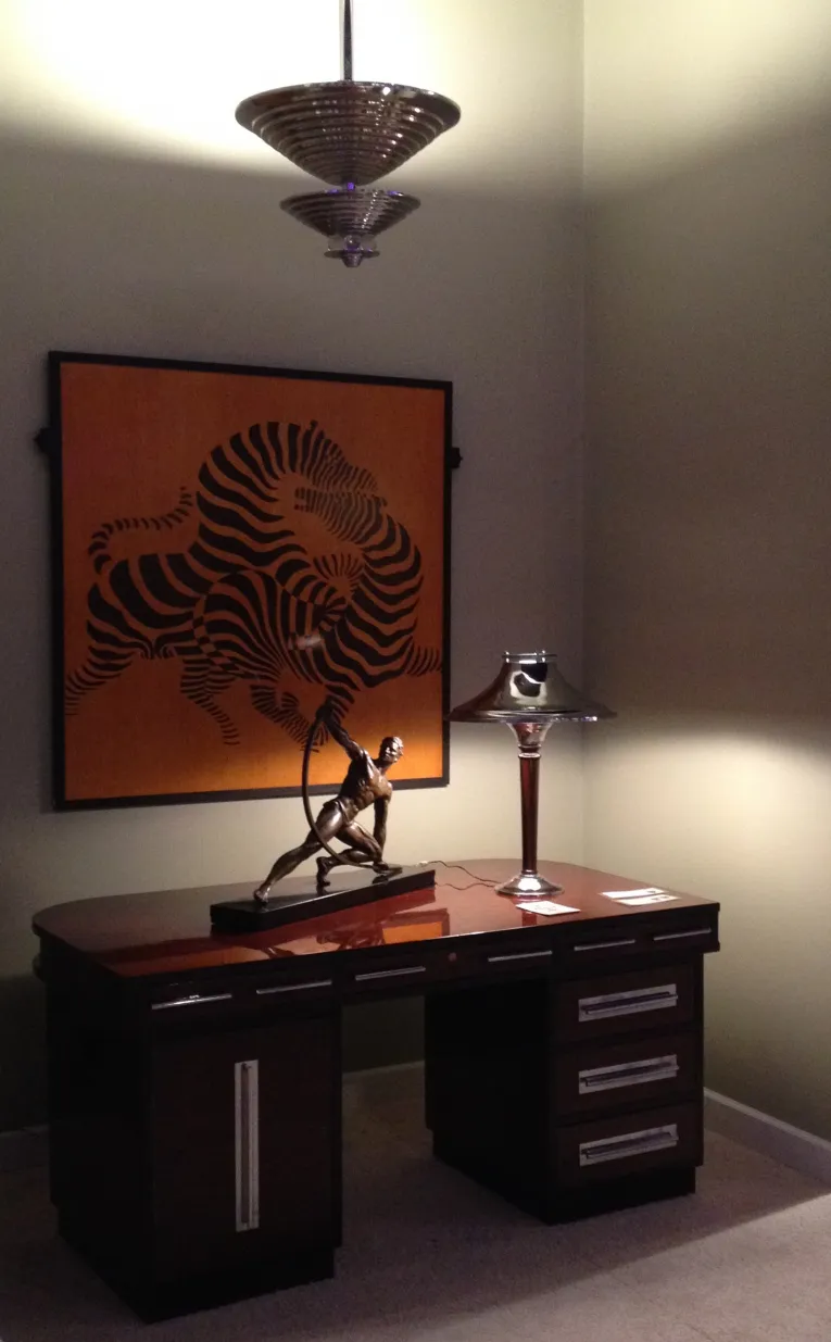 lampada a sospensione antica in stile art deco sopra una scrivania con scultura e quadro