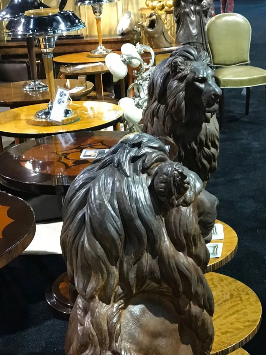 Deux lions anciens regardent droit devant eux dans un décor de meubles anciens.