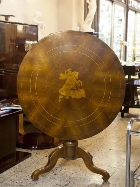 Table ronde ancienne avec un design décoratif et des pieds élégants dans un cadre sophistiqué.