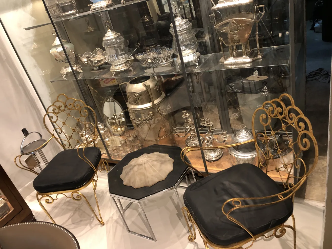 due poltrone da giardino antiche art deco con cuscini neri, decorate ed eleganti, in un ambiente di antiquariato