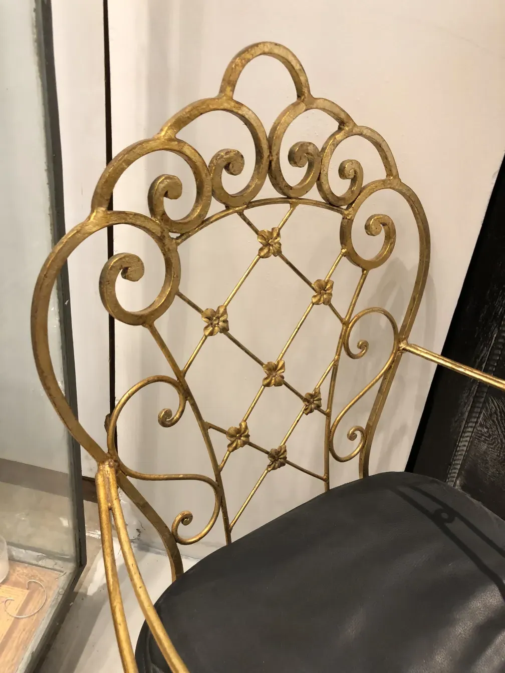 View of two antique garden armchairs with gold wrought iron, surrounded by a cozy setting.