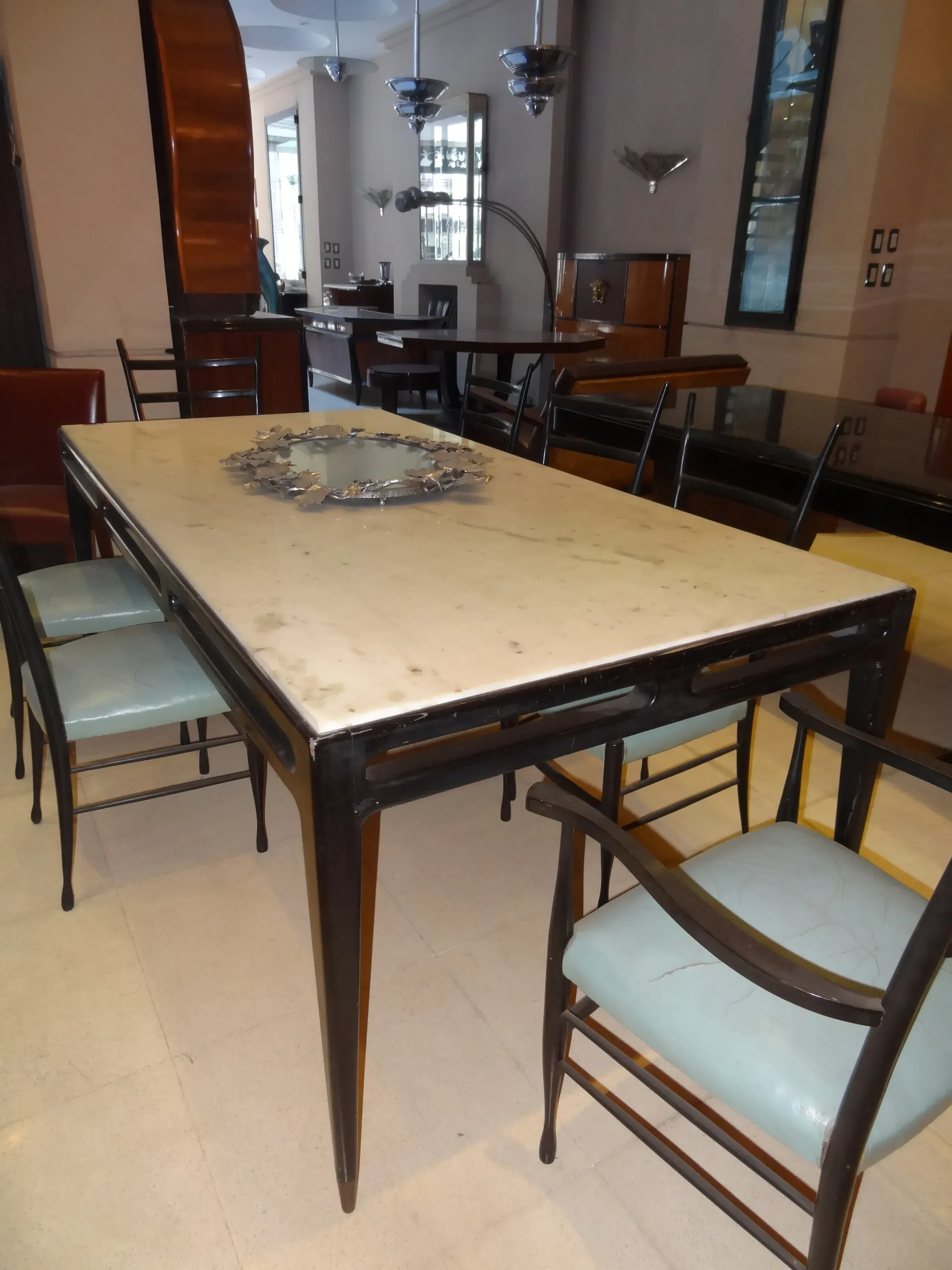 Antique dining table by Gio Ponti for 8 people, surrounded by chairs.