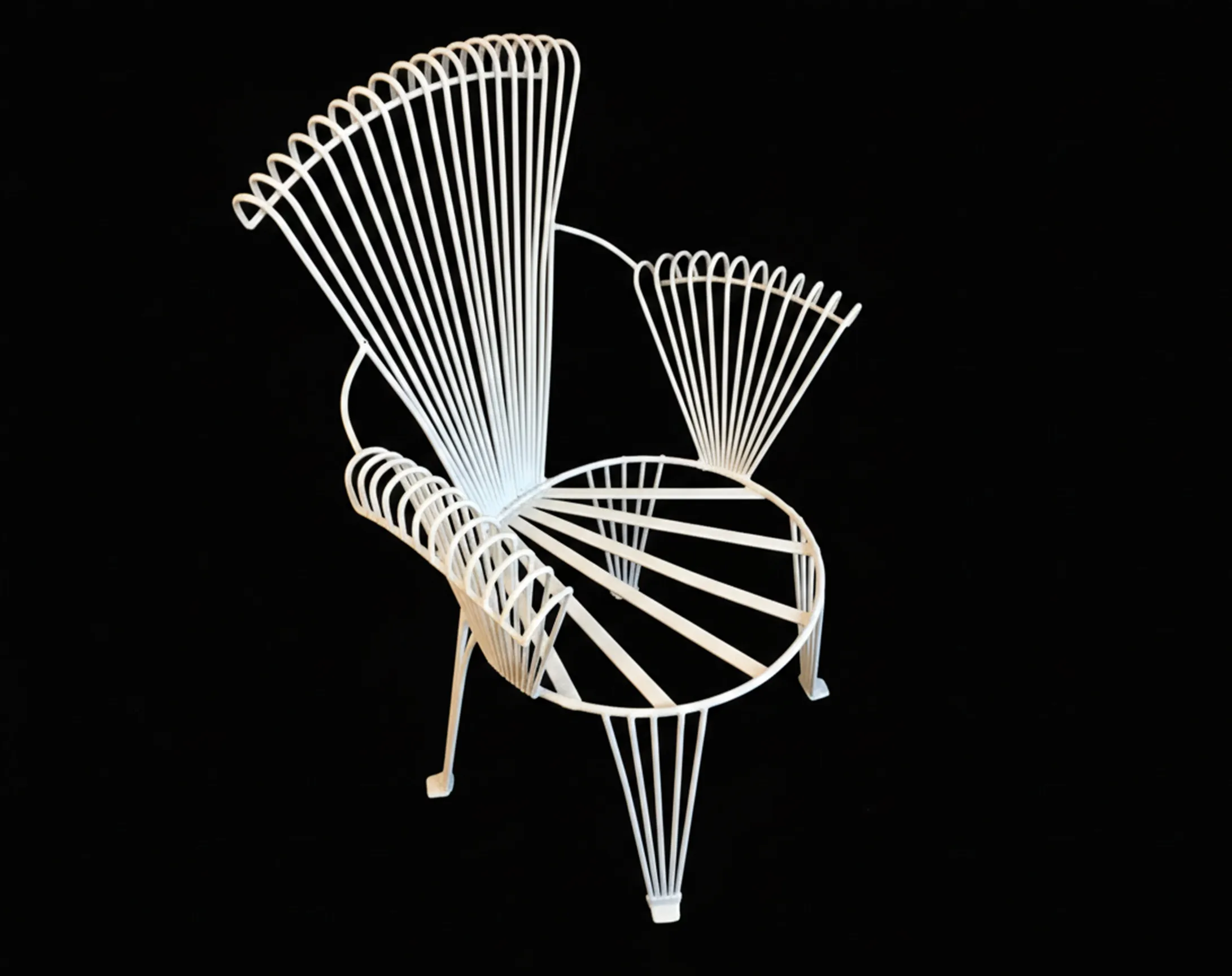 Quattro poltrone da giardino antiche con linee eleganti su sfondo scuro.