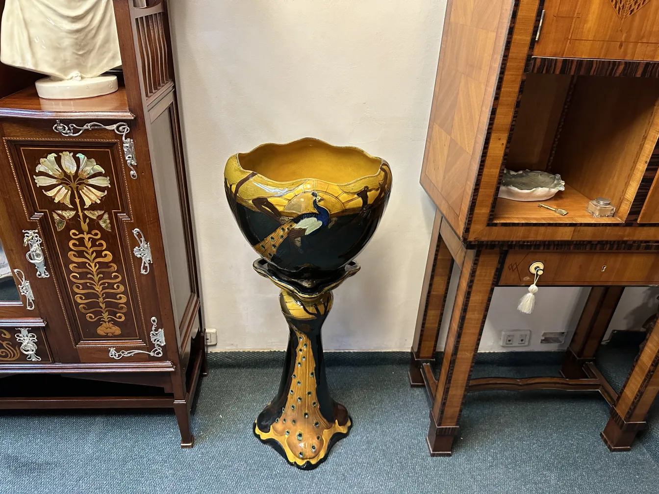 vaso de flores antigo em pé com detalhes ornamentais na base, fundo liso