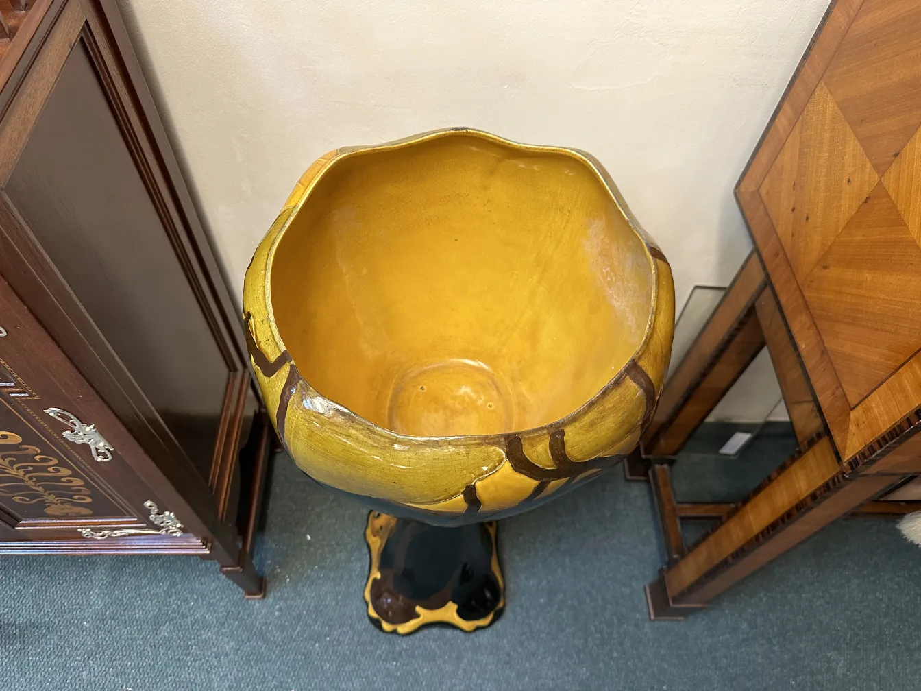 macetero antiguo con un interior amarillo y base decorativa, rodeado de muebles vintage