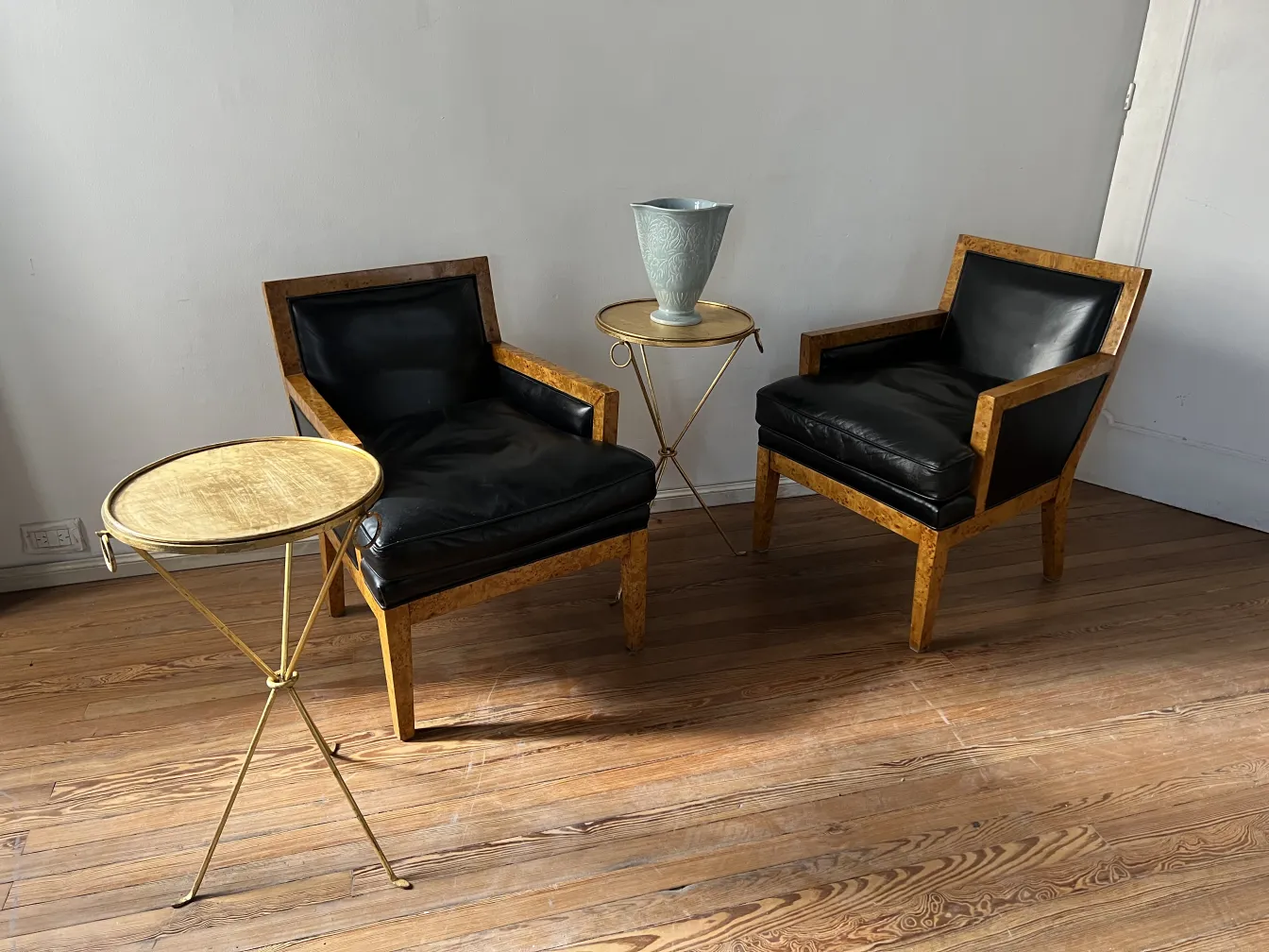 dos sillones antiguos con tapizado negro y estructura de madera clara, junto a una mesa auxiliar dorada