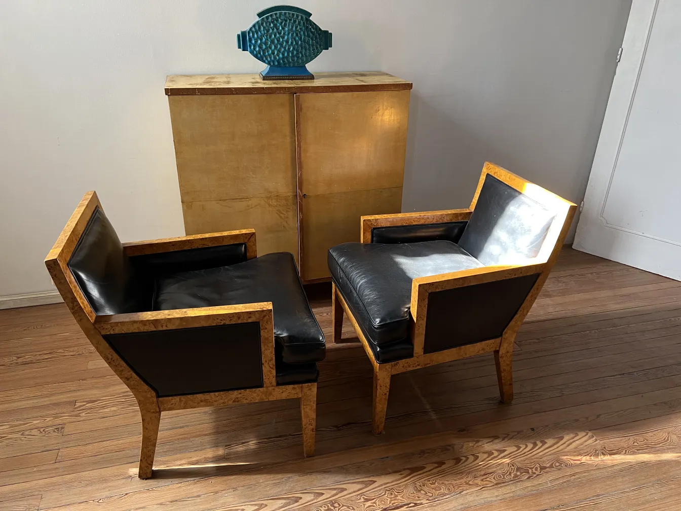 Dois antigos poltronas de designer Jean Michel Frank em um ambiente iluminado.