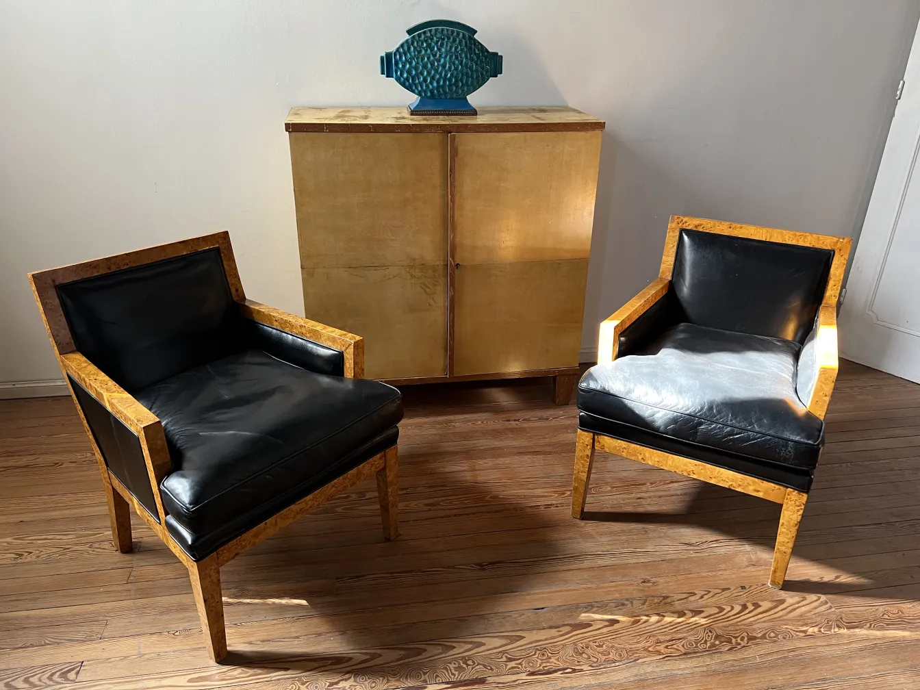 Deux fauteuils anciens avec un design élégant et des détails noirs, dans un cadre moderne.