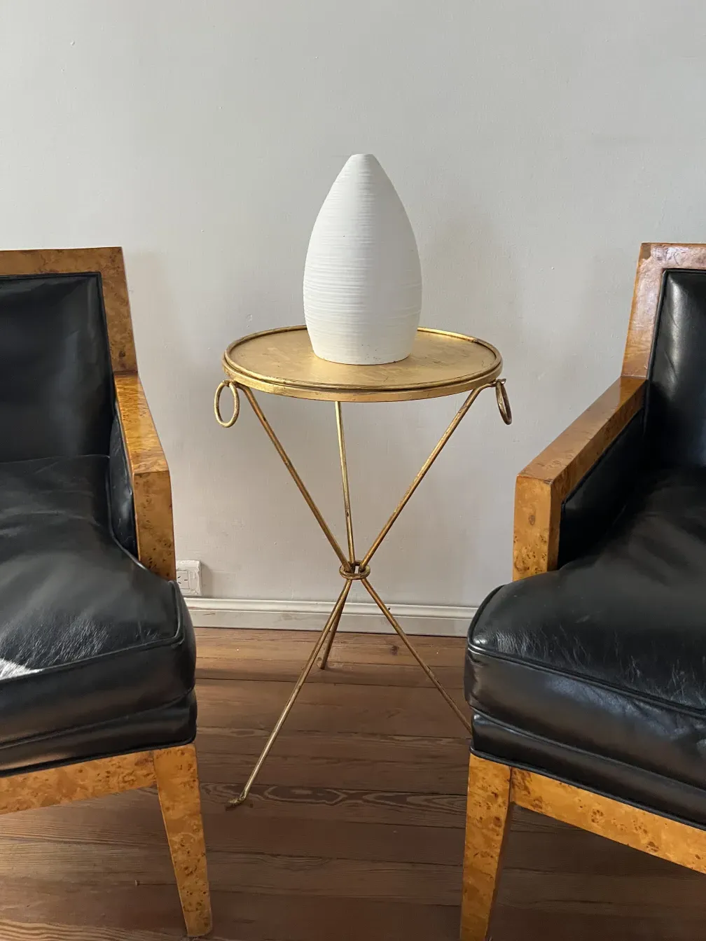 two antique armchairs by Jean Michel Frank, black leather, in a simple setting