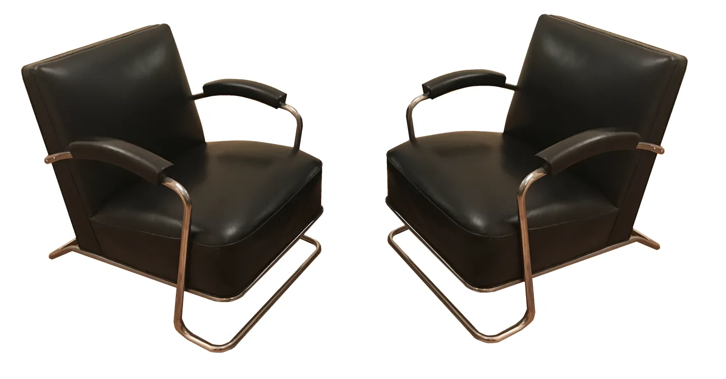 Dos sillones antiguos art deco de color negro, con brazos y base metálica.