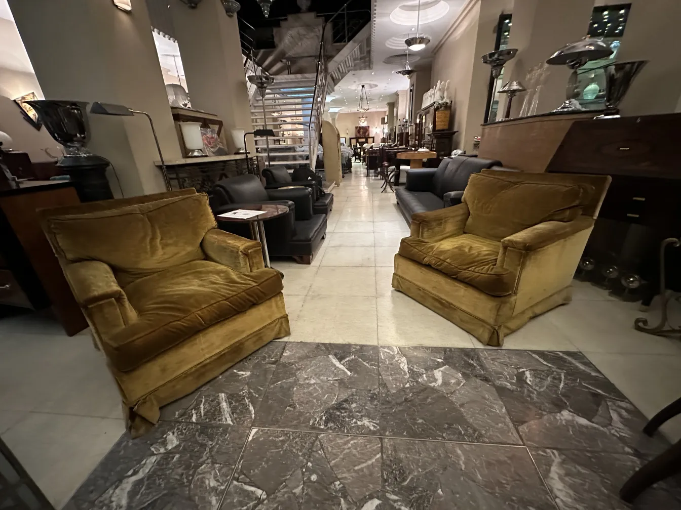 Due poltrone antiche in un ambiente elegante con vari mobili intorno.