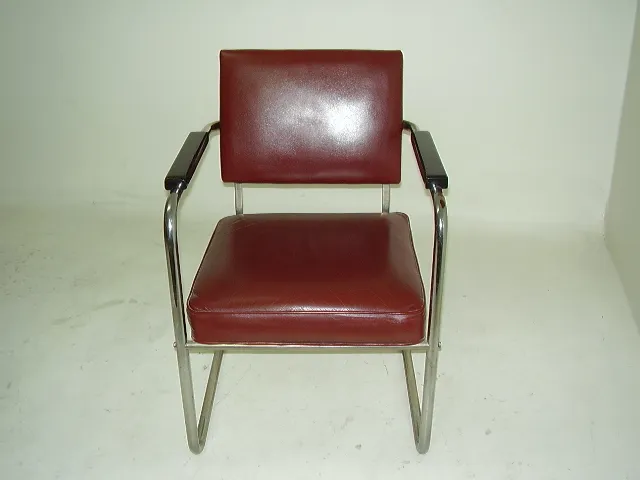 Dos sillones antiguos, uno con brazos y tapizado marrón, sobre fondo claro.