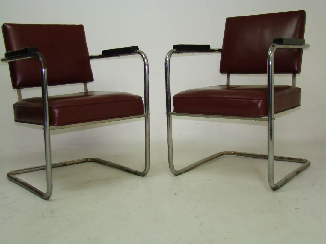 Two vintage armchairs with red upholstery on a neutral background.