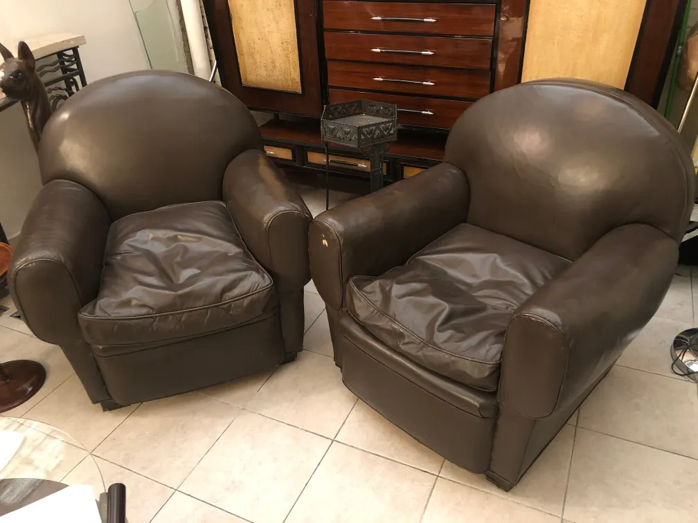 deux fauteuils anciens de forme arrondie, avec des coussins enfoncés, dans un environnement accueillant avec une décoration classique et moderne.