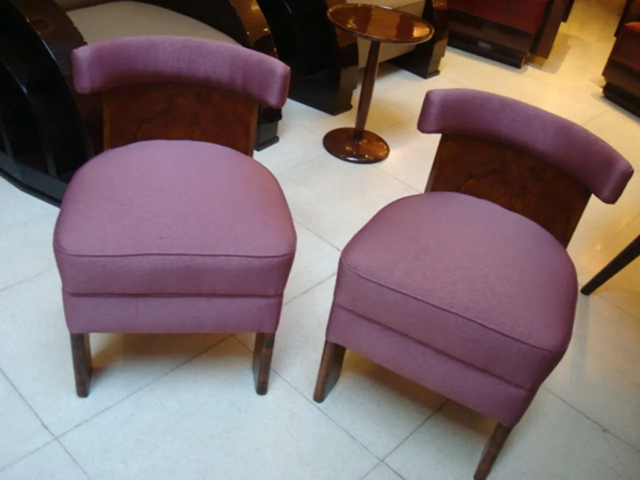 Deux fauteuils anciens de couleur violette dans un cadre classique.