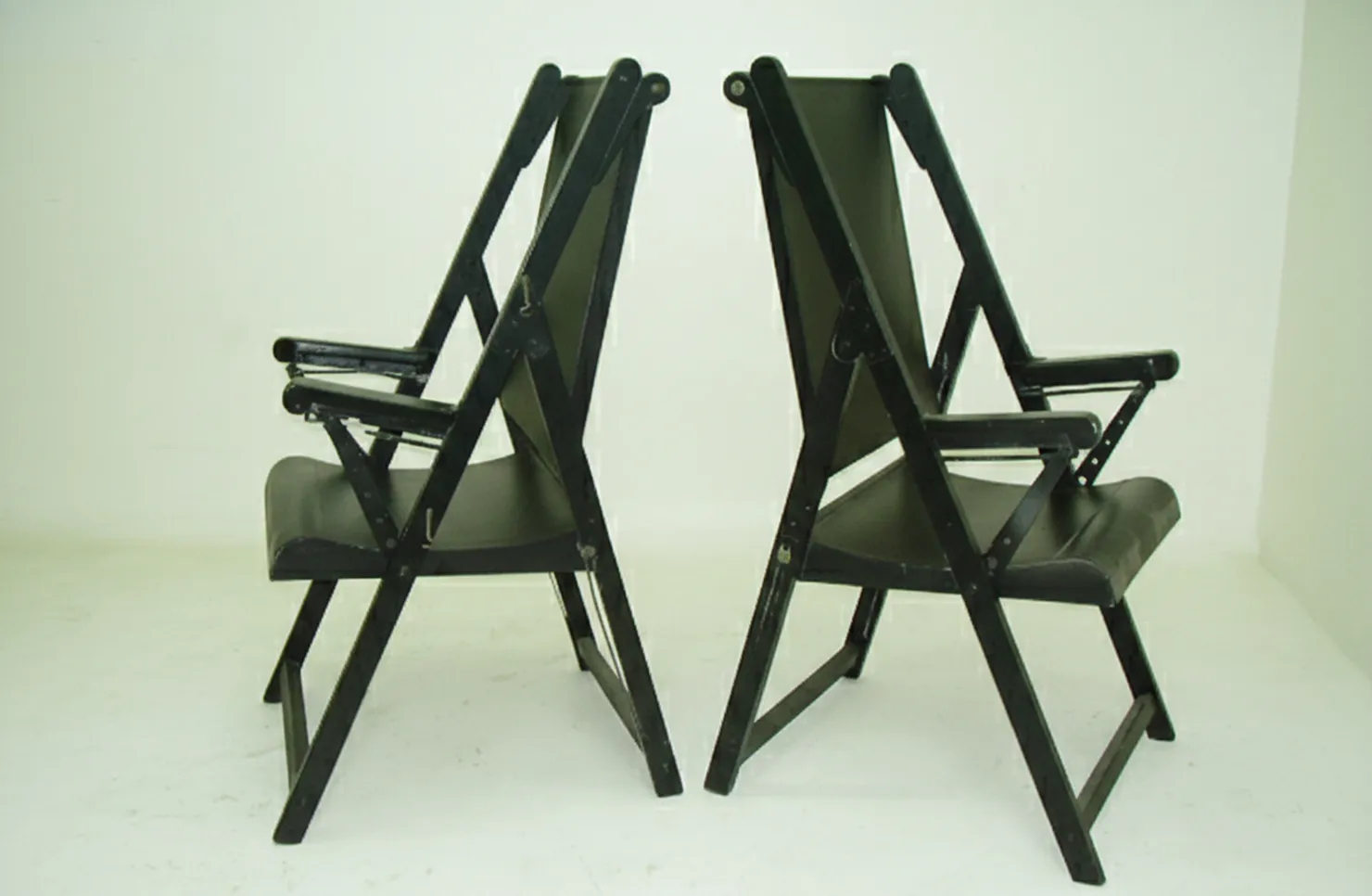 Zwei antike Sessel, die restauriert werden müssen, dunkle Farbe auf weißem Hintergrund mit Armlehnen.