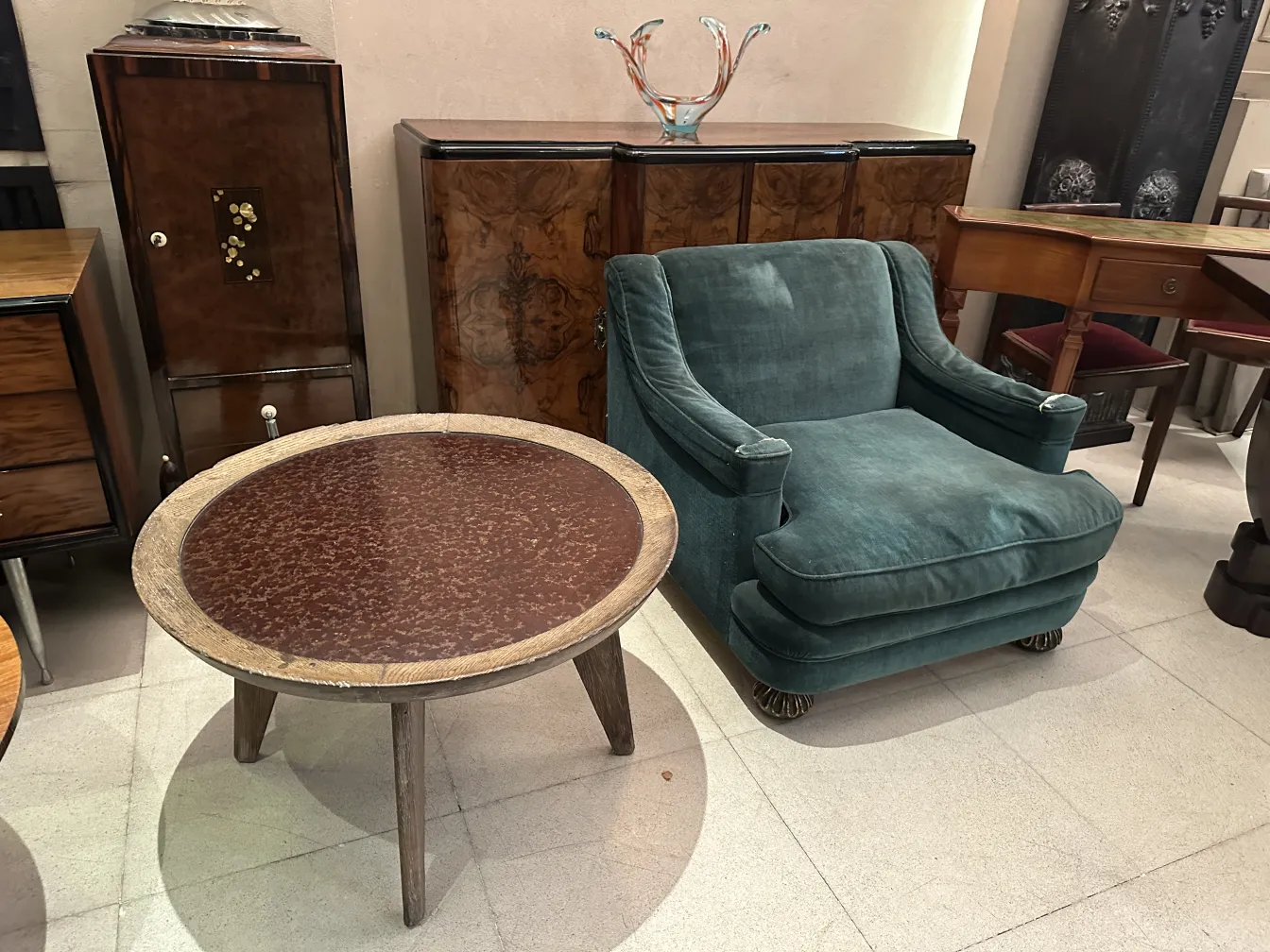 duas poltronas antigas, uma em tons de verde e uma mesa redonda.