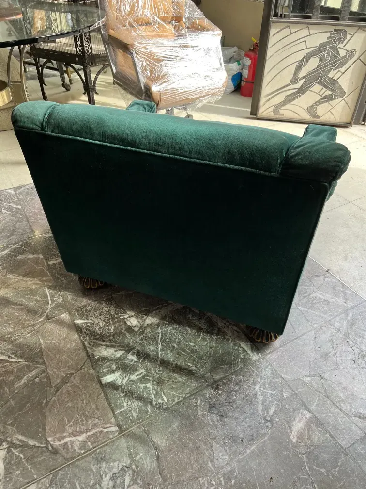 Duas poltronas antigas de cor verde escuro em um ambiente de restauração, com fundo decorativo.