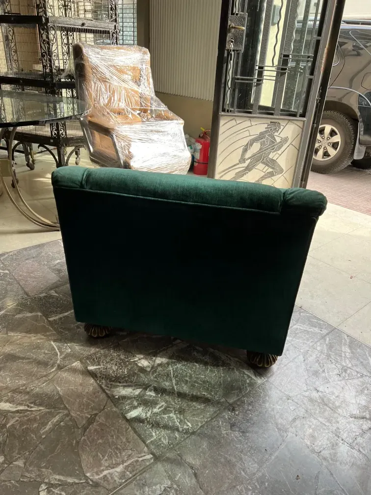 Due poltrone antiche verdi pronte per essere restaurate in un ambiente accogliente con altri mobili.