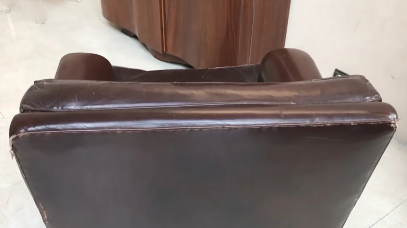 two antique armchairs to be restored, with a worn brown finish, in a classic setting.