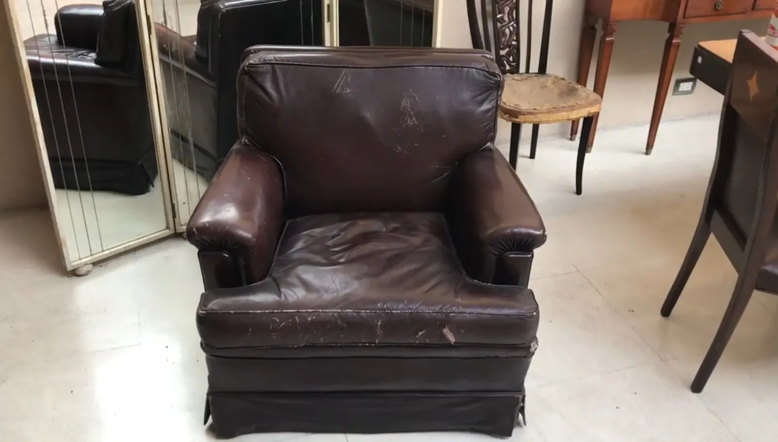 Deux fauteuils anciens montrant des signes d'usure, entourés de divers objets dans un cadre de restauration.