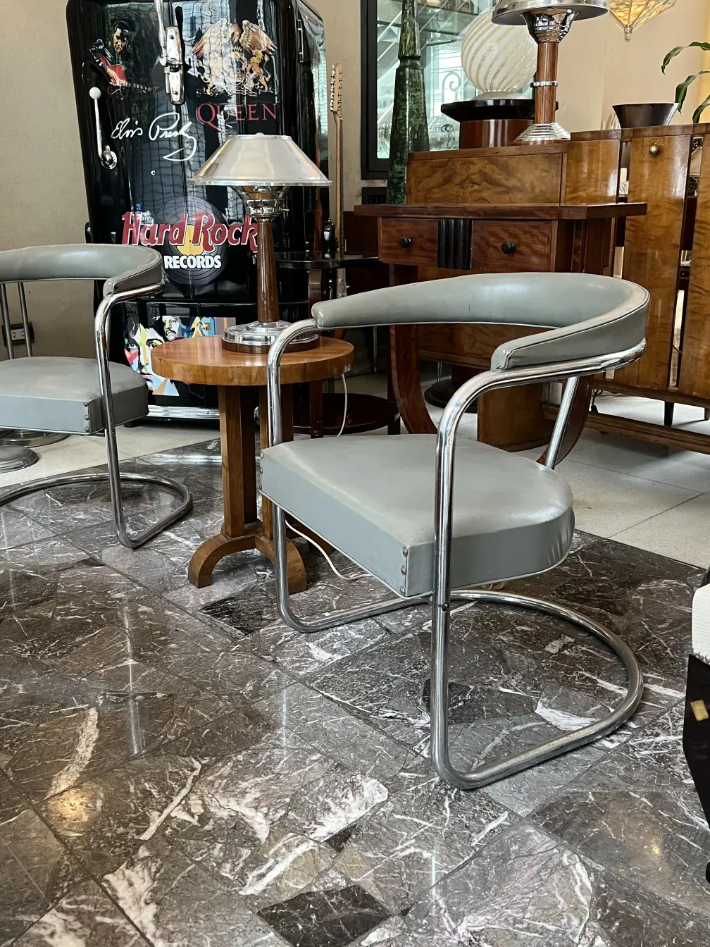 Zwei antike Sessel mit modernem Design zur Restaurierung, mit Metallrahmen und hellem Polster in einem Vintage-Ambiente.