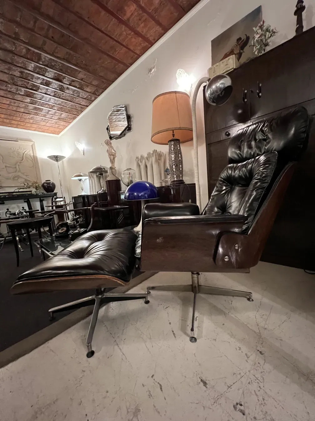 poltrona antica Herman Miller in attesa di restauro, in un ambiente con lampada e varie decorazioni.