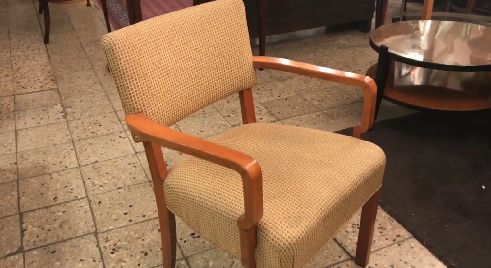 Sillón de escritorio antiguo con estructura resistente y brazos de apoyo, en un ambiente de oficina clásica.