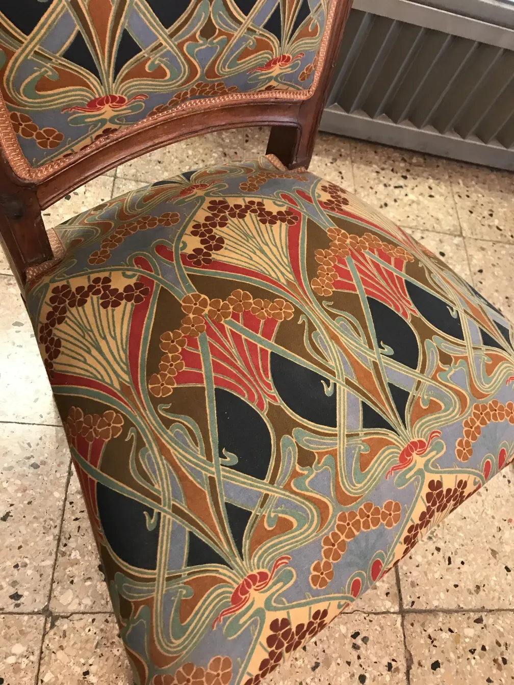 Antique chair with colorful floral design, cozy environment.