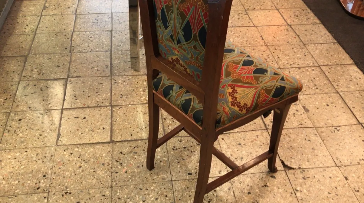 Sedia antica con design colorato in un ambiente moderno.