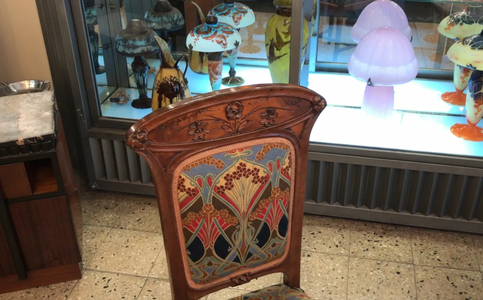 Antiker Stuhl im Art Nouveau-Stil mit buntem Polster und dekorativen Details.