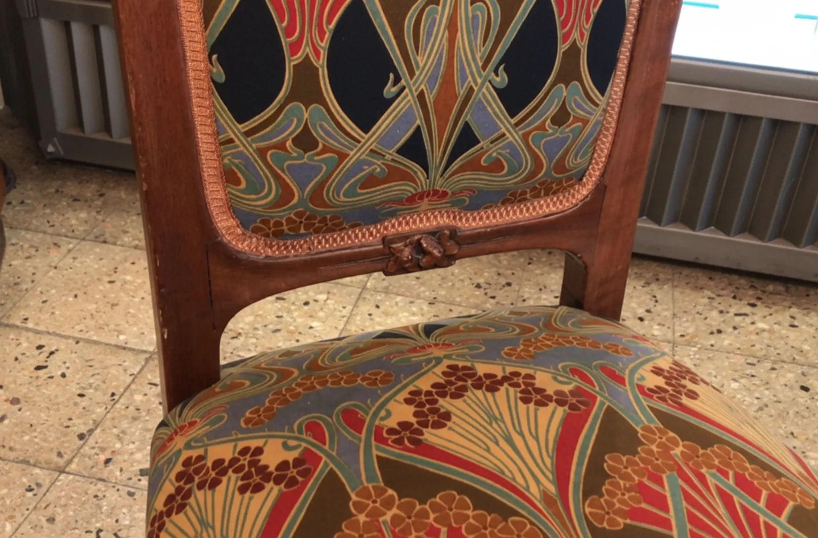 Silla antigua Art Nouveau con un diseño colorido y elegante en el respaldo y asiento.