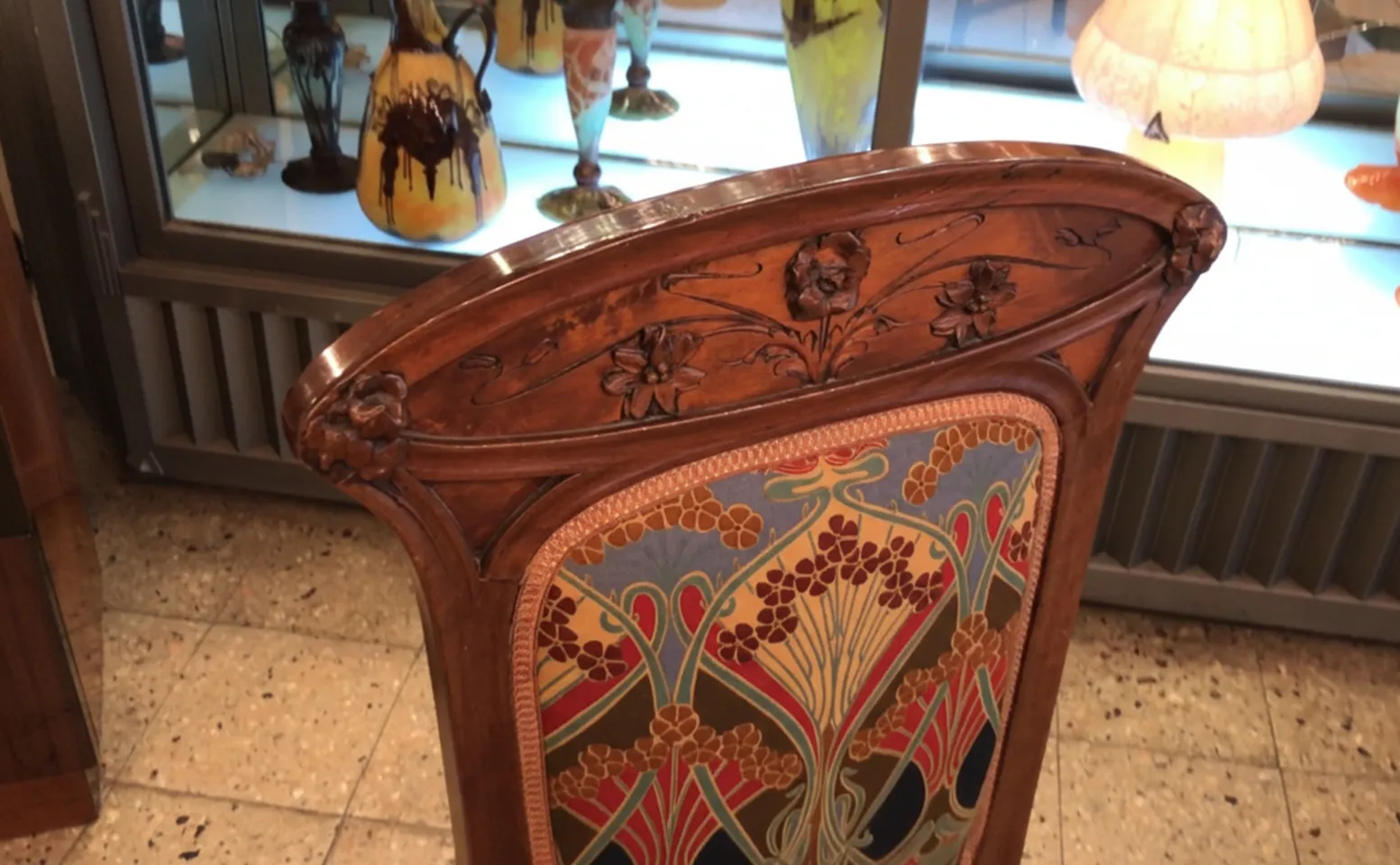 Antique chair featuring beautiful Art Nouveau design and vibrant colors, set among antiques.