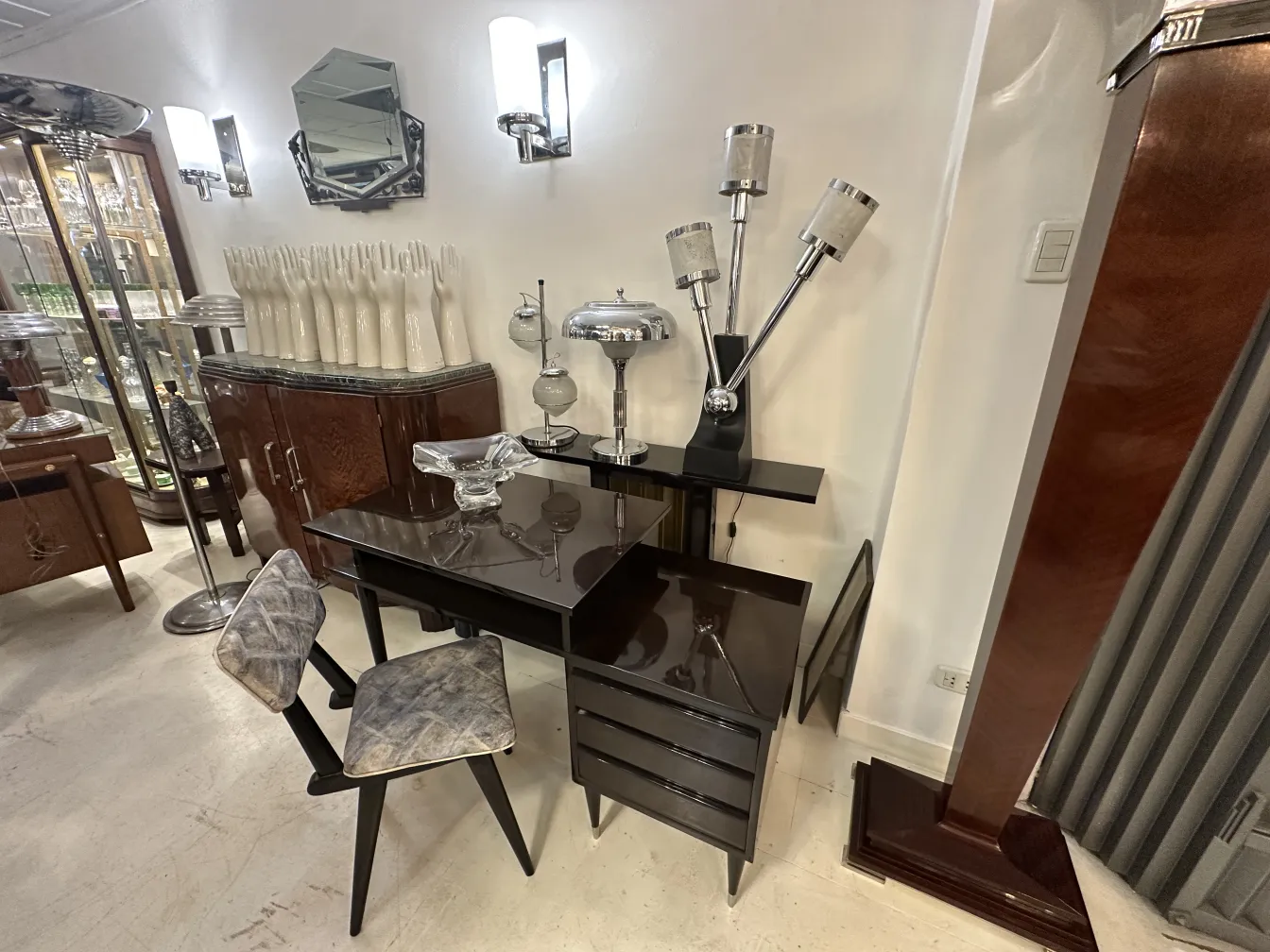 Imagens de duas cadeiras antigas ao lado de uma mesa elegante, em um ambiente bem iluminado com itens decorativos.