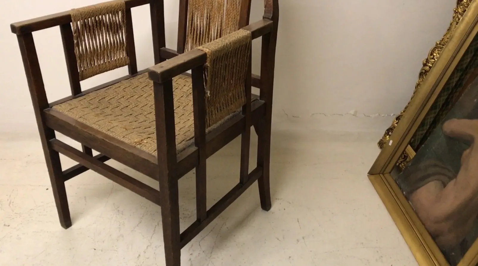 Sillón de escritorio antiguo con un diseño de asiento trenzado, en un ambiente minimalista.