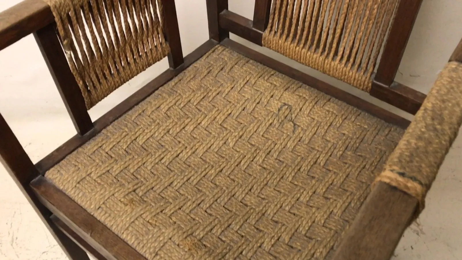 Cadeira de escritório antiga com design único e assento trançado, em um ambiente clássico.