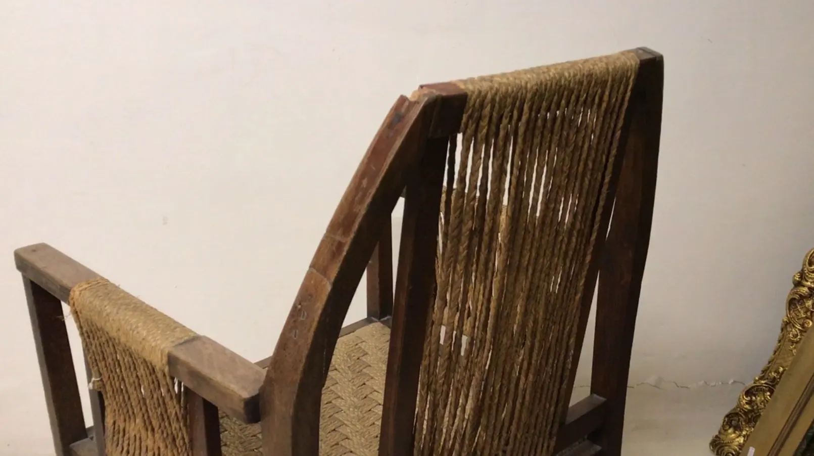 Sillón de escritorio antiguo con respaldo tejido en un entorno claro.