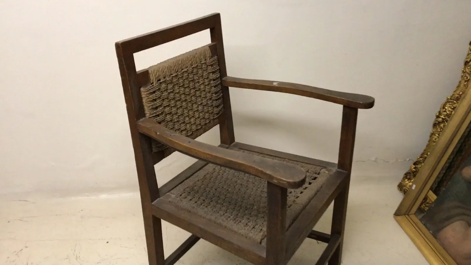 Fauteuil ancien avec bras dans un cadre simple.