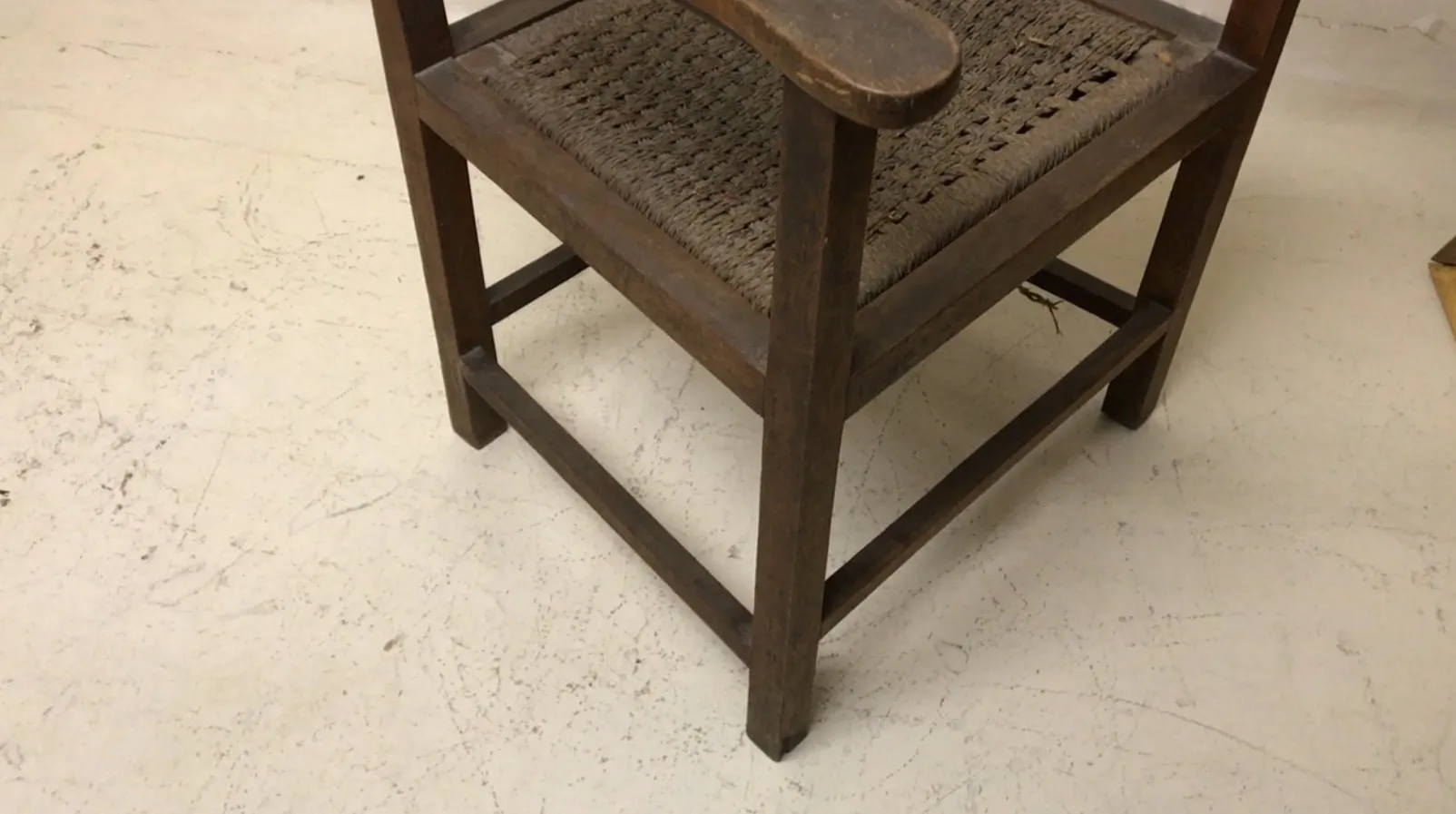 Sillón antiguo con brazos, en ambiente clásico.