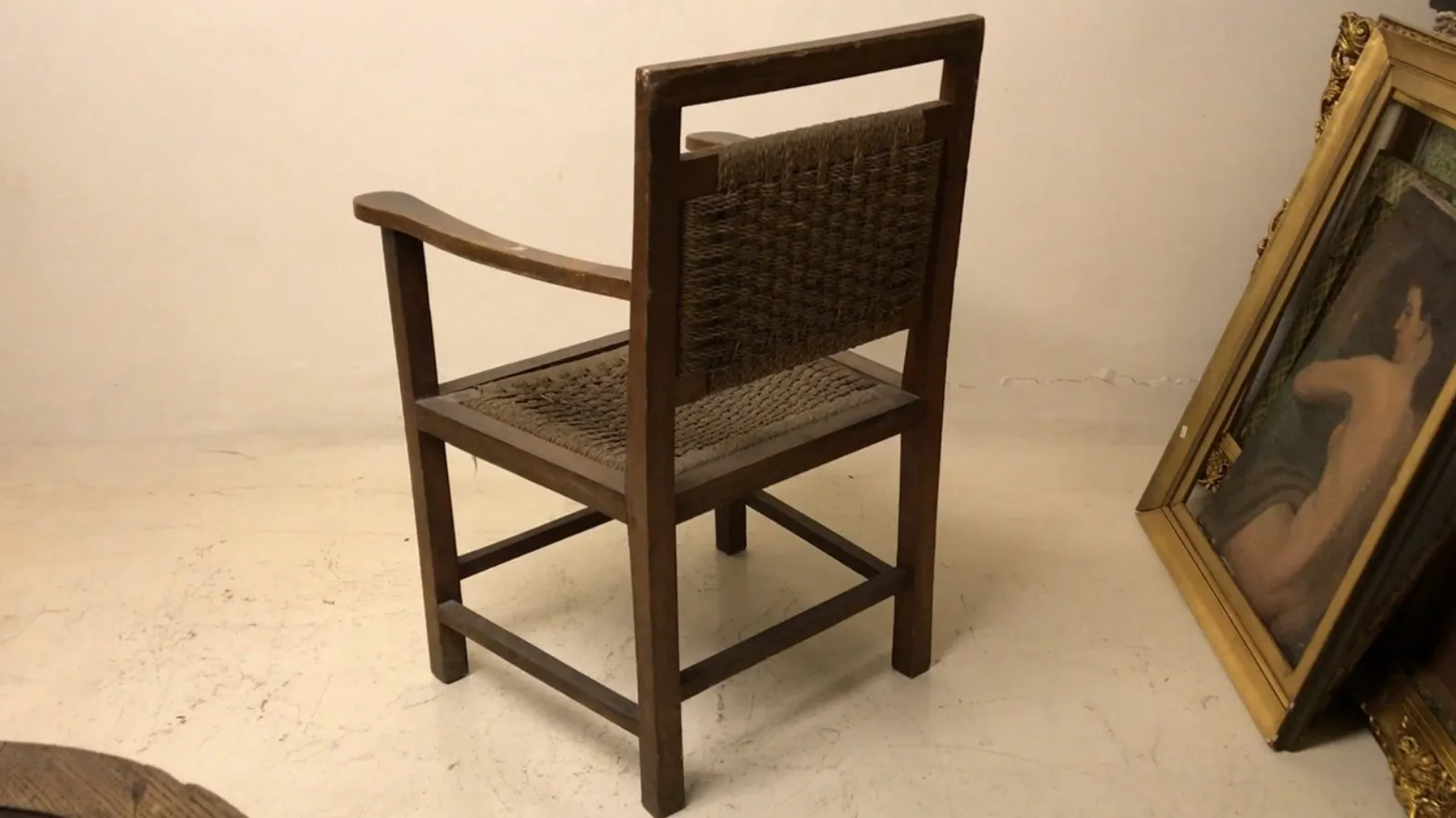 Sillón antiguo de estilo Art Nouveau con respaldo tejido, en un ambiente elegante.