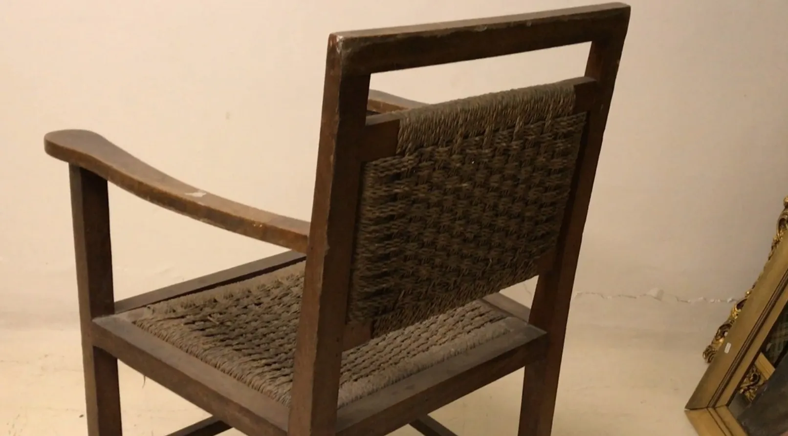 Fauteuil ancien avec dossier et accoudoirs, fond décoratif.