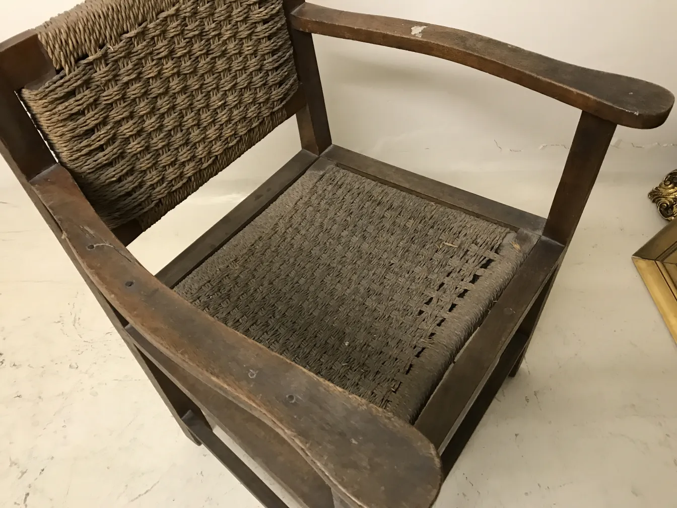 Antiker Sessel im Art Nouveau-Stil mit geflochtenen Details, neutraler Hintergrund.