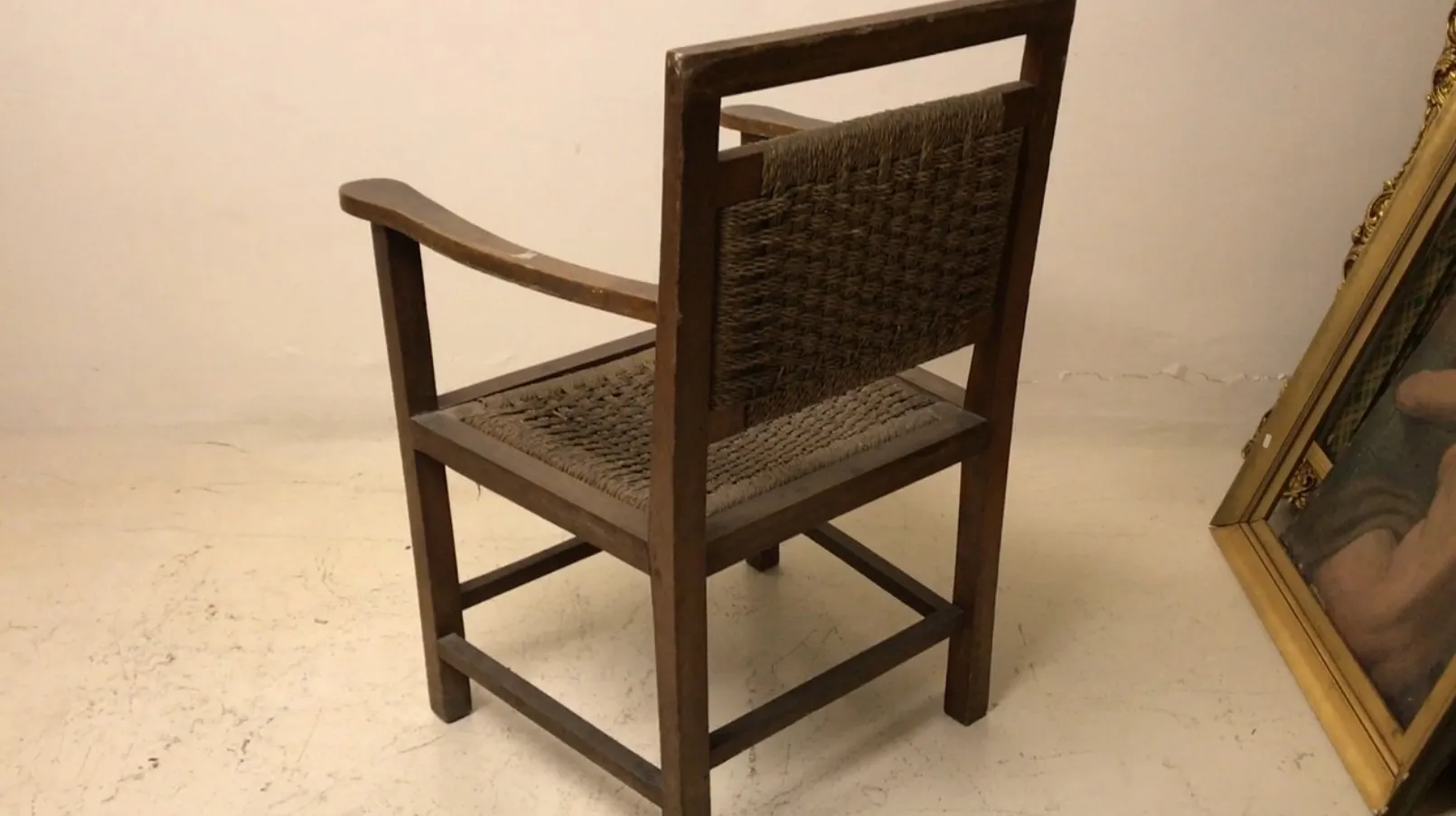 Fauteuil ancien de style Art Nouveau avec dossier haut et accoudoirs courbés dans un cadre simple.