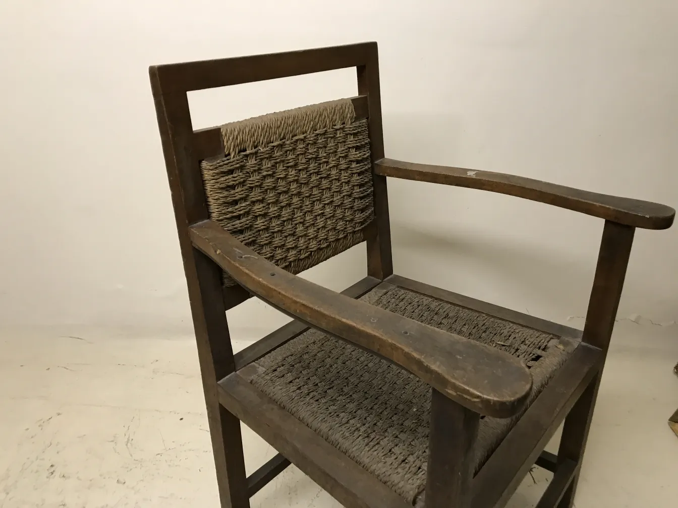 Poltrona antiga com braços de design clássico, fundo neutro.