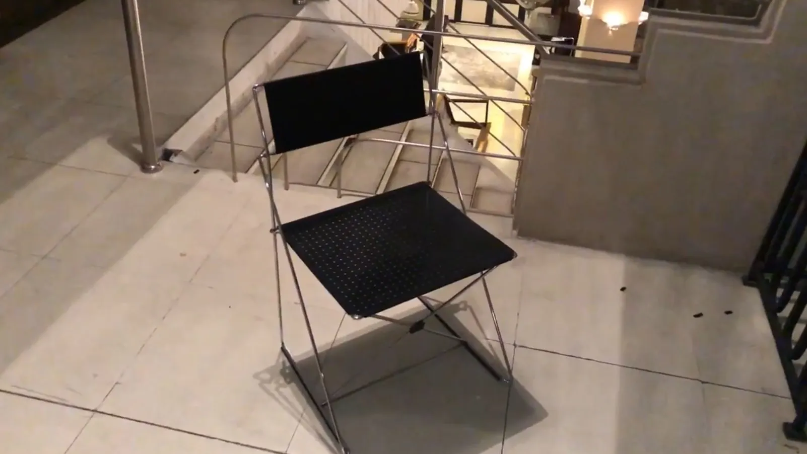 Zwei antike Stühle mit einfachem Design in einem eleganten Ambiente, mit Treppen im Hintergrund.