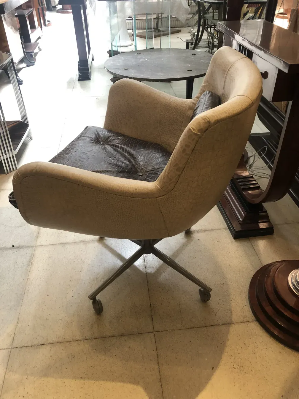 Sillón antiguo suave color beige con ruedas en la base.