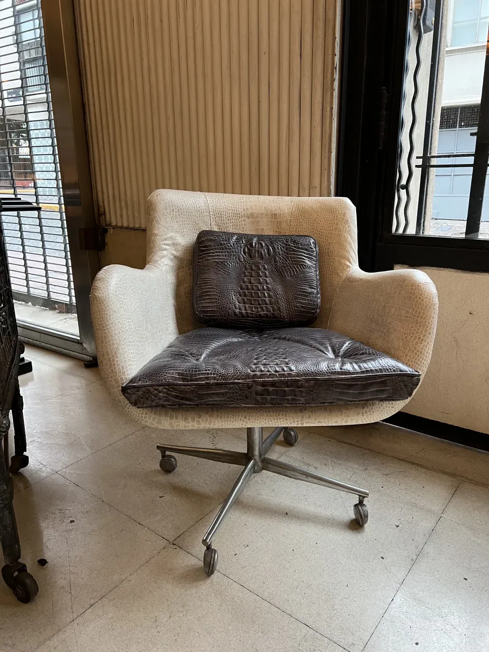 Poltrona antiga com design ergonômico e almofada decorativa em um ambiente elegante.