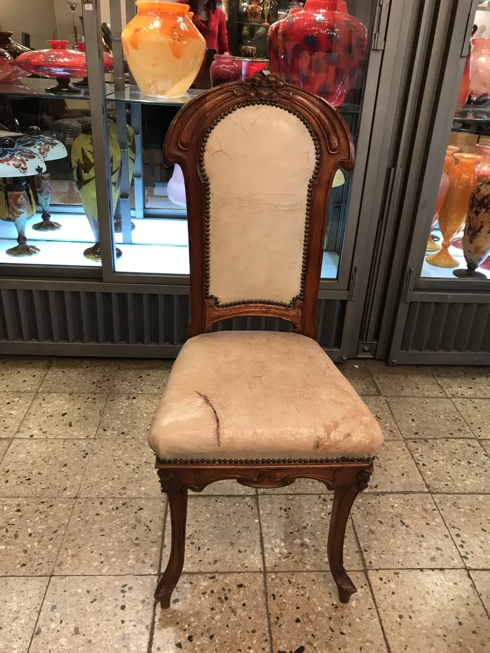 Silla antigua con respaldo alto, estilo art nouveau, ambiente con objetos decorativos.