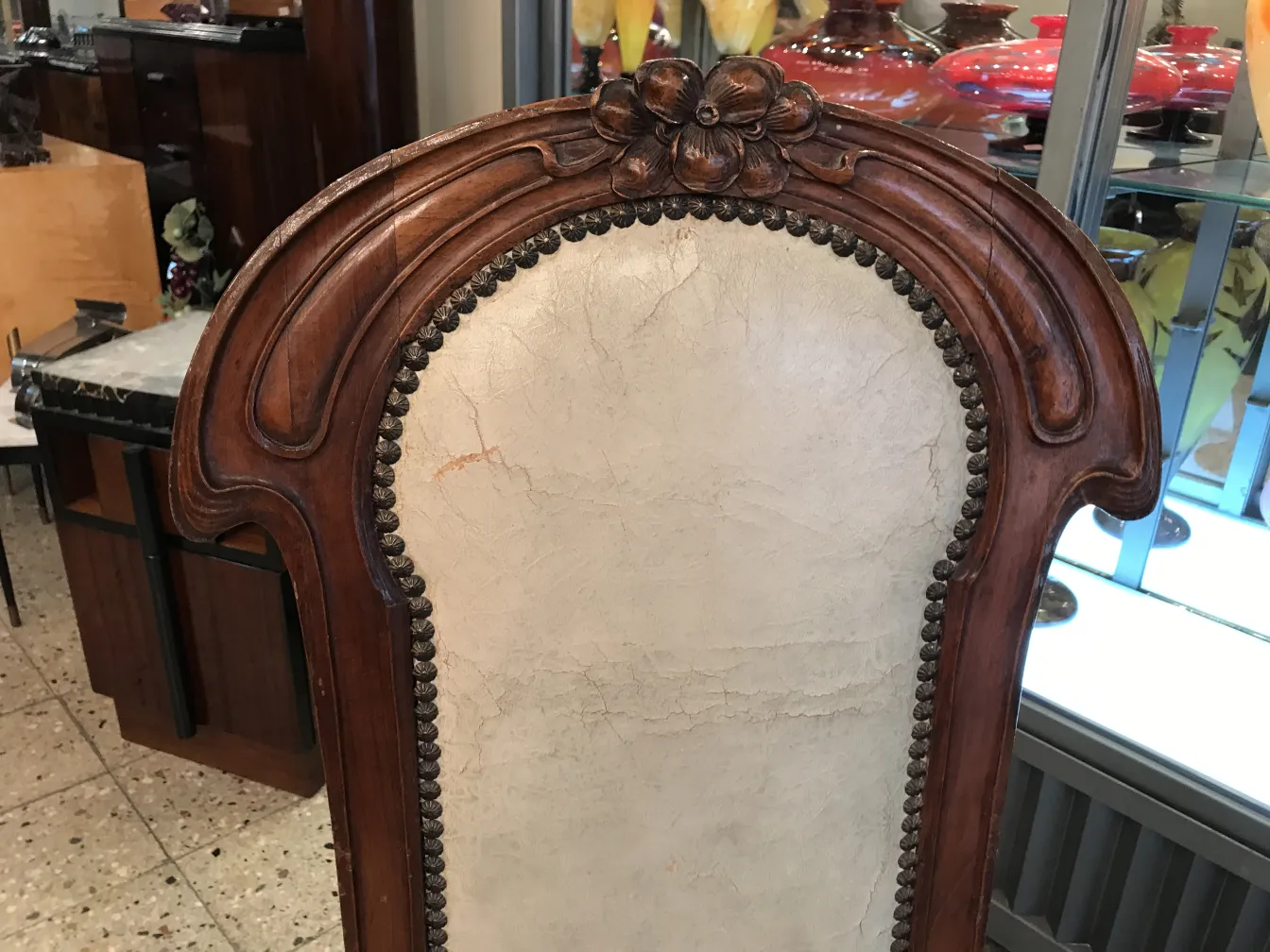 cadeira antiga com detalhe na parte superior, cercada por outros itens