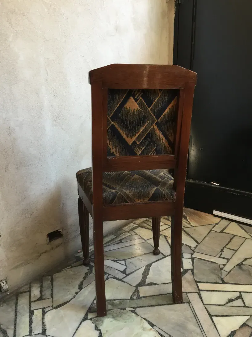 2 antique chairs with unique design on tiled floor.